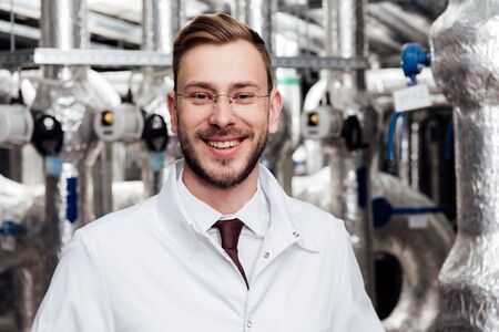 cheerful engineer in glasses and white coat looking at camera