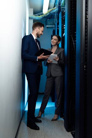 cheerful businesswoman and businessman with clipboard in data centerの写真素材