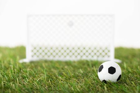 selective focus of toy soccer ball and football gates on green field isolated on white, sports betting conceptの写真素材