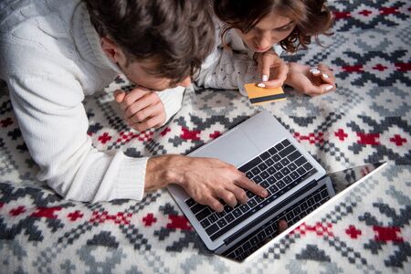 high angle view of boyfriend pointing with finger at laptop and girlfriend holding credit cardの写真素材