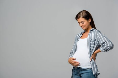 happy pregnant woman touching belly isolated on greyの写真素材