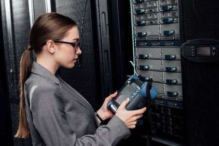 side view of businesswoman holding reflectometer in data center