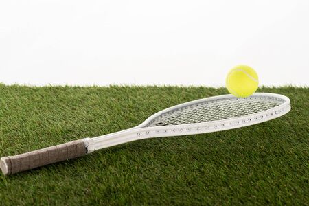 tennis racket and ball on green grass isolated on white, sports betting conceptの写真素材