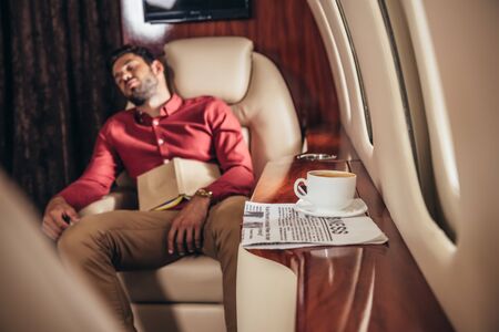 handsome man in shirt sleeping with book in private planeの写真素材