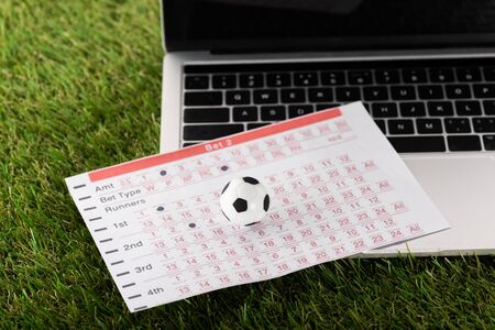 toy soccer ball and betting list near laptop on green grass, sports betting conceptの写真素材