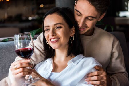 happy man looking at woman with glass of red wine