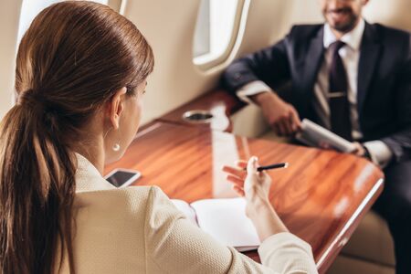 selective focus of businessman and businesswoman talking in private planeの写真素材