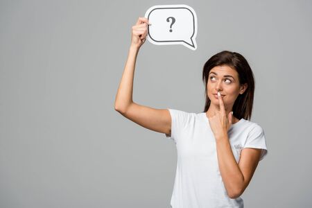 thoughtful woman holding speech bubble with question mark, isolated on greyの写真素材