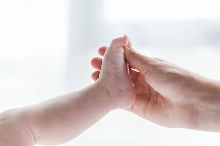 cropped view of woman doing massage while touching leg of infant baby