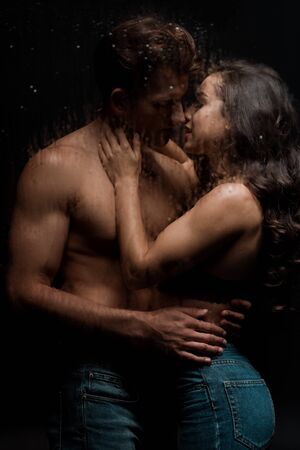 beautiful passionate couple hugging and kissing behind wet glass