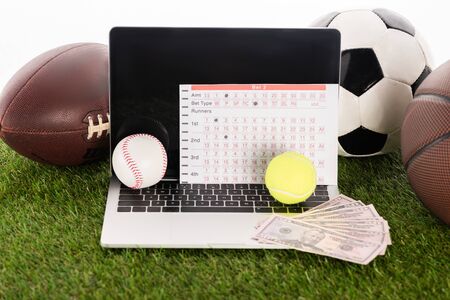 laptop near sports balls and betting list on green grass isolated on white, sports betting conceptの写真素材