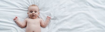 panoramic shot of adorable baby lying on bed at home