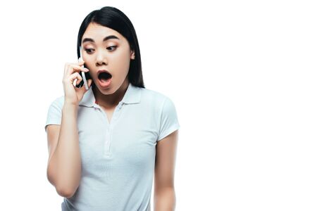 surprised attractive asian girl with open mouth talking on smartphone isolated on whiteの写真素材