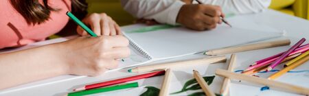 panoramic shot of babysitter drawing with kid in living room