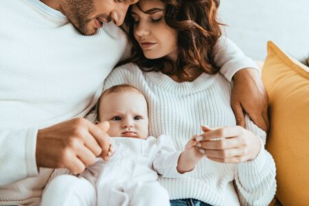 cropped view of man hugging beautiful wife holding little daughterの写真素材