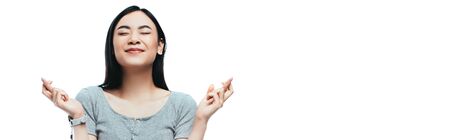 asian girl with closed eyes and crossed fingers isolated on white, panoramic shot