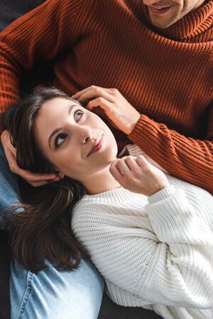 high angle view of attractive girlfriend in sweater smiling and lying on knees of boyfriendの写真素材
