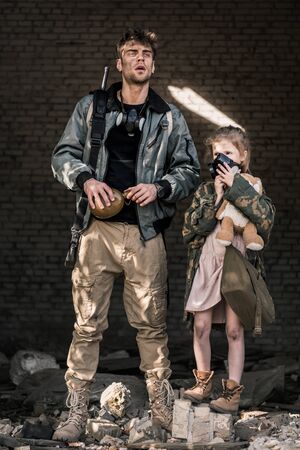 handsome man holding flask near kid in gas mask, post apocalyptic conceptの写真素材