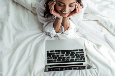 high angle view of smiling woman looking at laptop at morningの写真素材