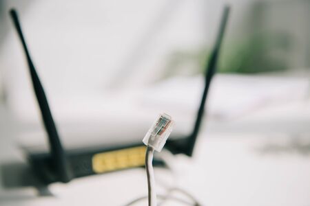 selective focus of wire with connector near black router on white tableの写真素材