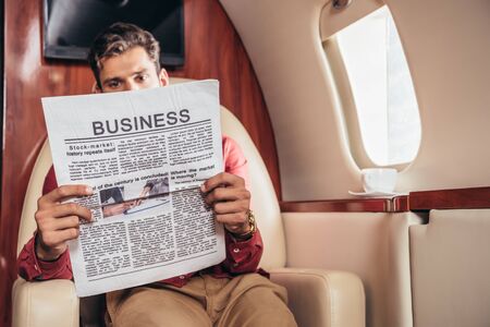 handsome man reading business newspaper in private planeの写真素材