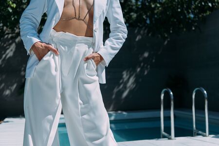 cropped view of woman in white suit posing outside