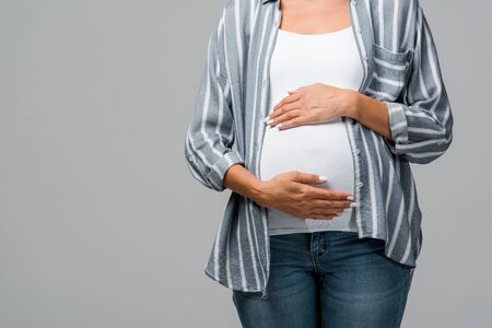 cropped view of pregnant girl touching tummy isolated on grey