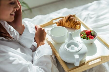 cropped view of woman in white shirt having breakfast in bed at morningの写真素材