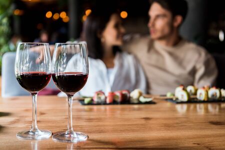 selective focus of glasses with red wine near happy man and womanの写真素材