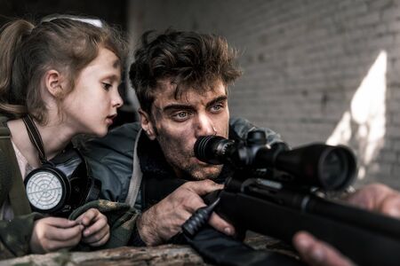 selective focus of kid looking at man with gun, post apocalyptic conceptの写真素材