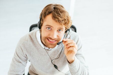 overhead view of cheerful bearded broker looking at camera in officeの写真素材