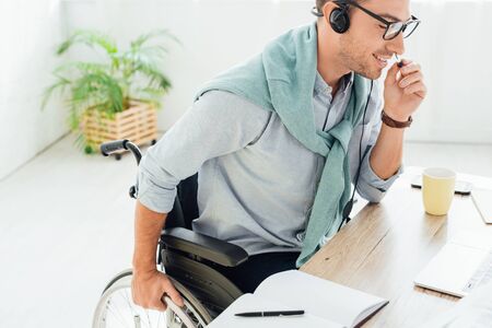 Smiling call center operator in wheelchair talking on headset