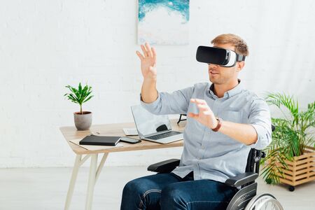 Disabled man using virtual reality headset in living roomの写真素材