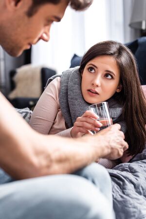 cropped view of boyfriend giving glass of water to sick girlfriendの写真素材