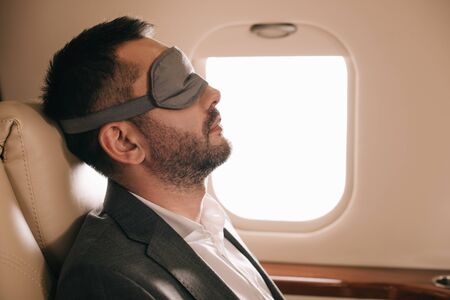 side view of businessman in sleeping mask sitting in private jetの写真素材