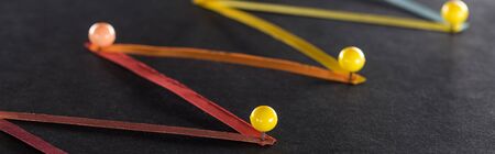 panoramic shot of multicolored abstract connected lines with pins on black background, connection...