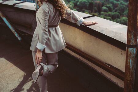 cropped view of elegant trendy woman posing in beige suit on urban roofの写真素材