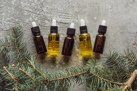 top view of bottles with naturaloil near fir branches on grey stone surfaceの写真素材