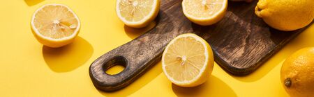 ripe cut lemons on wooden cutting board on yellow background, panoramic shotの写真素材