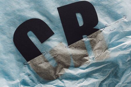 black c and r letters immersed in paper symbolizing water on grey paper backgroundの写真素材