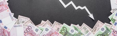 panoramic shot of white recession arrow near dollar and euro banknotes on black backgroundの写真素材