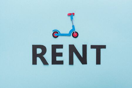 top view of paper cut kick scooter and black rent lettering on blue backgroundの写真素材