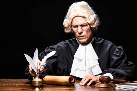 judge in judicial robe and wig taking feather isolated on blackの写真素材