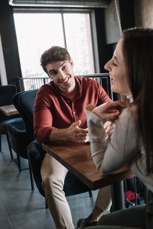 happy couple talking while drinking coffee on balcony in coffee shopの写真素材