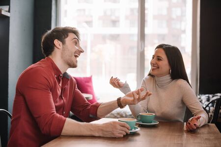 happy young couple talking in coffee shopの写真素材