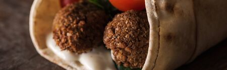 close up view of falafel with sauce and vegetables in pita, panoramic shotの写真素材