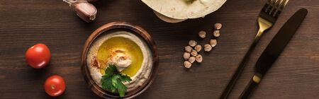top view of vegetables near cutlery, spices and hummus on wooden table near spices, panoramic shotの写真素材