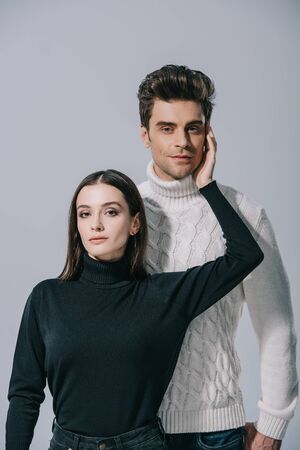 fashionable couple posing in white and black autumn sweaters, isolated on greyの写真素材