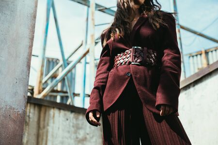 cropped view of elegant girl posing in trendy burgundy suit on urban roofの写真素材