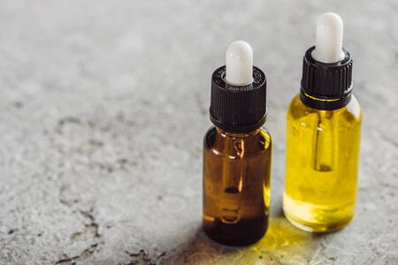 close up view of bottles with natural serum on grey stone surfaceの写真素材